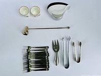 All items laid out: forks, serving fork, candle snuffer, tongs, coasters in holder, porcelain cups