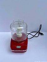 Front view showing red base, clear bowl, blade and power cord