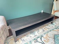 full view of black rectangular coffee table with open shelf