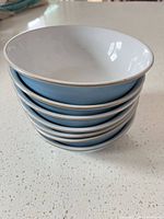 Stacked set of seven blue stoneware bowls showing exterior color and rim