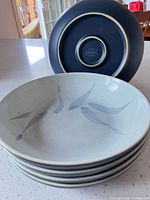 Stack of five Denby Spirit pasta bowls showing interior leaf pattern and one bowl turned to show base
