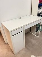 Front left angle of white laminate desk showing drawer and open space on right