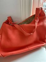 Front view of coral leather shoulder bag on white surface