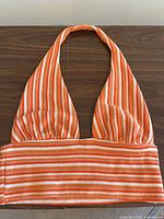 Front of orange-white striped knit halter crop top