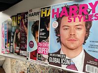 Row of nine Harry Styles magazines on shelf, spines and covers partially visible