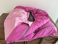 Two-tone pink youth sleeping bag folded on table