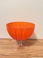 Full view of orange ribbed bowl on clear stem