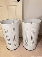 Both white metal perforated hampers upright