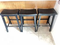 Three black wooden bar stools side-by-side