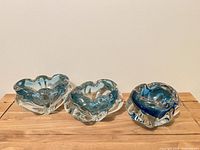 Front view of three blue and clear glass ashtrays