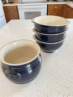 Stacked view of four navy exterior, cream interior soup bowls on countertop