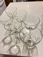 Six clear glass champagne coupes on countertop