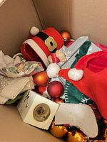 Box view showing hats, glass ornaments, napkins, candle holder