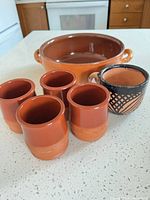 Group view of casserole dish, four cups and patterned mug