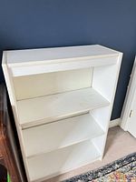 Front view of white engineered wood bookshelf showing three shelves and back panel