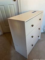 Front and side view of white 3-drawer dresser showing knobs and overall wear