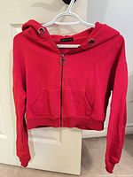 Front view of red cropped hoodie on hanger showing full-zip, pockets and hood