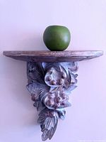 Front view of carved grape motif shelf with apple for scale