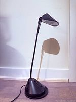 Full view of black halogen desk lamp standing upright