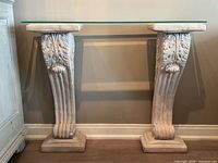 Full view of console table with glass top on two carved plaster legs