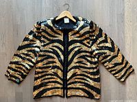 Front view of black and gold sequin tiger stripe jacket on hanger