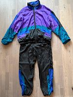 Full view of Badge windbreaker jacket and pants laid flat