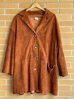 Full front view of rust suede leather jacket on hanger showing overall design and length