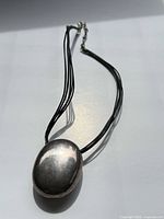 Full view of leather necklace with sterling oval pendant