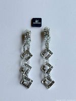 Full view of both Swarovski clip-on earrings and logo tag