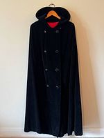 Front view of black velvet hooded cape on hanger