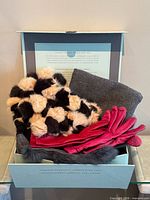 Box containing two-tone rabbit fur scarf, grey wool scarf, red leather gloves, grey fur item visible
