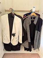 Collection of jackets, blazers and dress hanging in closet