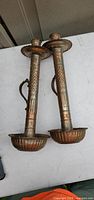 Two tall metal candle holders lying on table