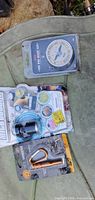 All three sealed items laid out: compass, microscope, whistle