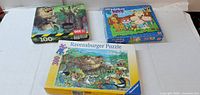 Front view of three puzzle boxes: Ravensburger 300-piece, wildlife wolf 100-piece, Maggie and the Ferocious Beast puzzle