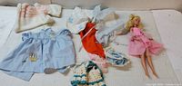 Wide view of Barbie doll and several clothing pieces on table