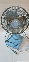 Front view of light blue Holmes Air desk fan showing grille, blades, base and cord