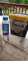Finish Ultimate detergent pouch and Glisten cleaner bottle, front view