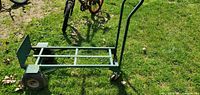 Full view of green steel hand truck in horizontal position on grass