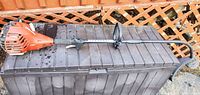 Full view of Homelite curved-shaft trimmer on storage bin