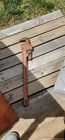 Full view of red pipe wrench on wooden decking