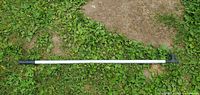 Full view of aluminum boat hook pole lying on grass showing hook end and length