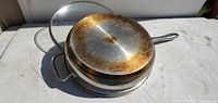 Bottom view showing stainless steel pan base, helper handle, wear marks