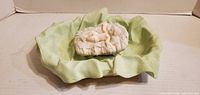 Baby Jesus figurine resting in green blanket inside manger