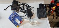 All items laid out: Olympus wired accessory, AC adapter, Zip-Zapper package, earbuds, camera case