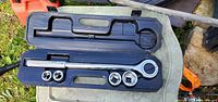 Open case showing ratchet wrench and four sockets
