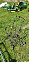 Full view of black folding metal cart standing upright on grass