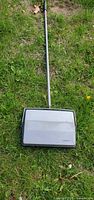 Full view of Bissell manual sweeper lying on grass