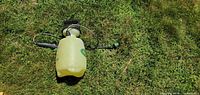 Top view of complete Scotts pump sprayer on grass showing tank, hose, pump handle and wand