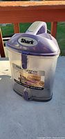 Front view showing Shark logo, clear bin and latch